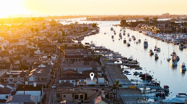 aerial view at dusk featuring a water view and a residential view