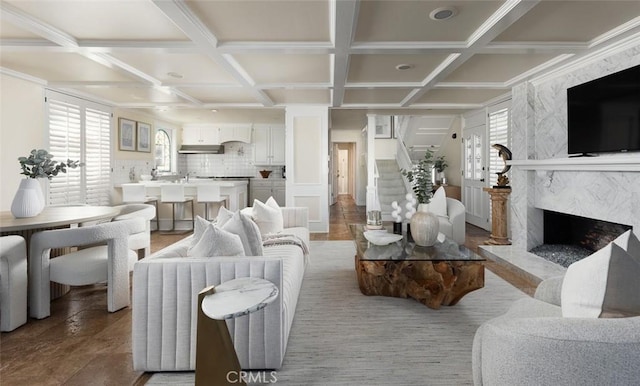 living room with a fireplace, stairway, coffered ceiling, and beamed ceiling