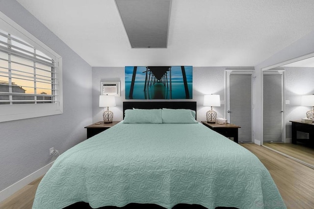 bedroom featuring a wall mounted AC and light hardwood / wood-style flooring