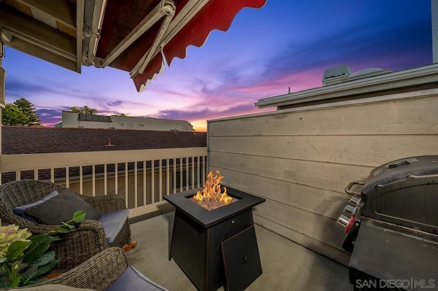 patio terrace at dusk featuring grilling area and an outdoor fire pit