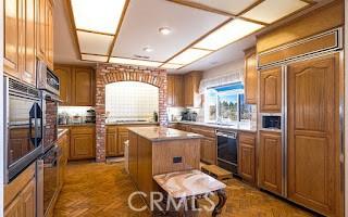 kitchen with dishwasher, parquet floors, a center island, wall oven, and paneled refrigerator