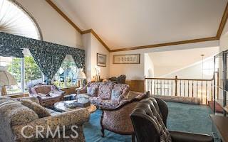 carpeted living room featuring high vaulted ceiling and ornamental molding