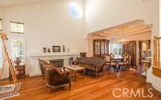 interior space with hardwood / wood-style flooring, a raised ceiling, a high ceiling, and a notable chandelier