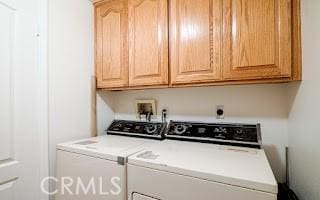 clothes washing area featuring cabinets and washer and dryer