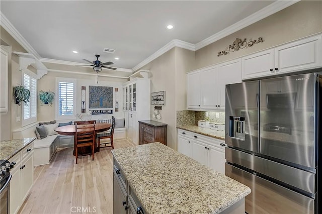 kitchen featuring white cabinetry, decorative backsplash, light stone counters, breakfast area, and stainless steel appliances