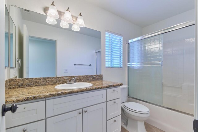 full bathroom with shower / bath combination with glass door, vanity, and toilet