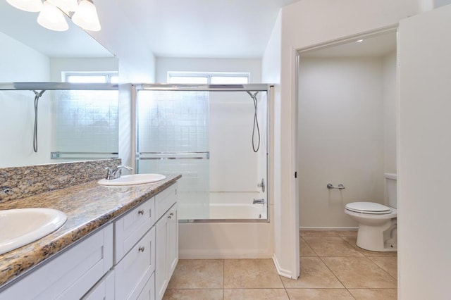 full bathroom featuring tile patterned flooring, bath / shower combo with glass door, vanity, and toilet