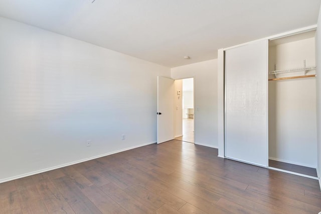 unfurnished bedroom with dark hardwood / wood-style floors and a closet