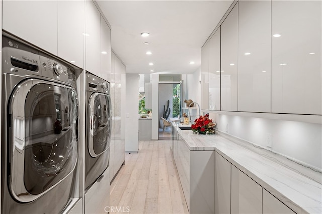 4727 Alonzo Ave, Encino, CA 91316 - laundry area featuring separate washer and dryer, sink, light hardwood / wood-style flooring, and cabinets