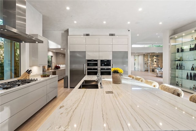 4727 Alonzo Ave, Encino, CA 91316 - kitchen with wall chimney exhaust hood, sink, light stone counters, stainless steel appliances, and white cabinets
