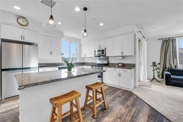 kitchen with stainless steel appliances, a center island, white cabinets, and a kitchen bar