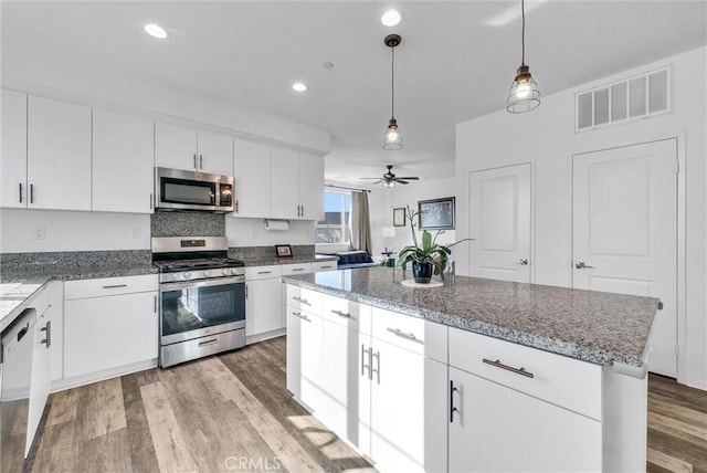 kitchen featuring pendant lighting, light hardwood / wood-style flooring, white cabinetry, stainless steel appliances, and a center island