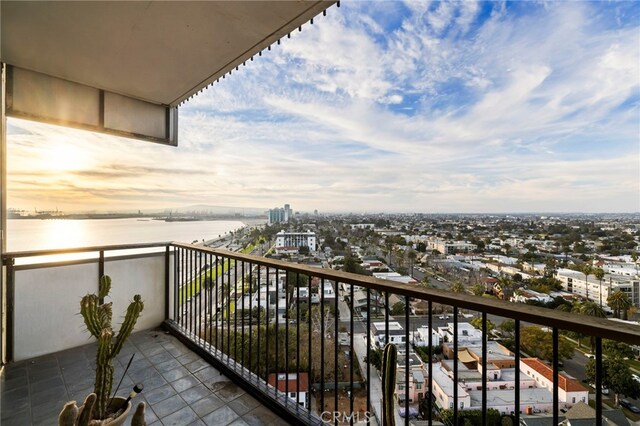 balcony at dusk featuring a water view