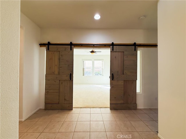 interior space with light tile patterned flooring and a barn door