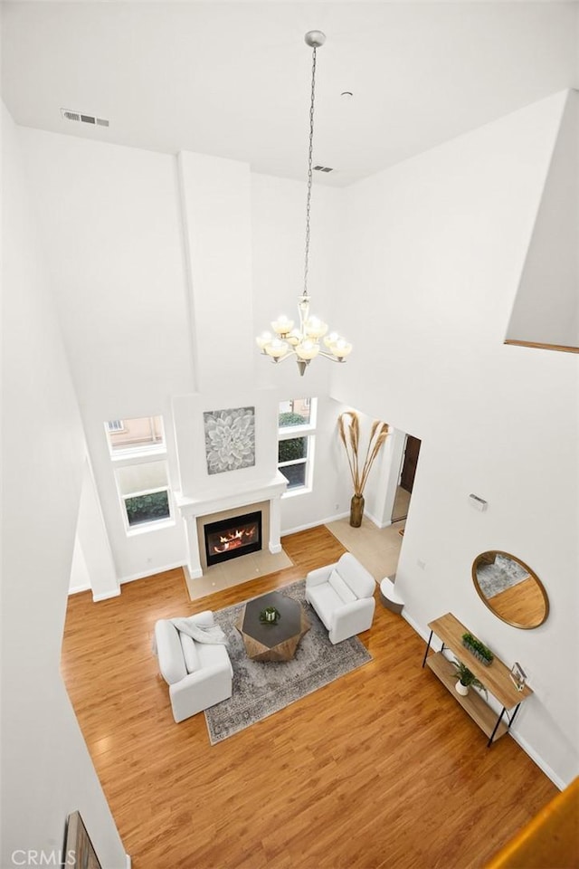 living room featuring wood-type flooring, a chandelier, and high vaulted ceiling