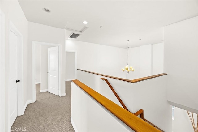 hallway featuring light carpet and a notable chandelier