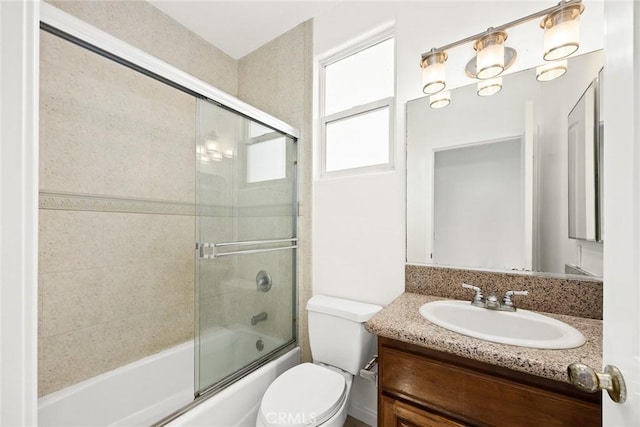 full bathroom featuring vanity, bath / shower combo with glass door, and toilet