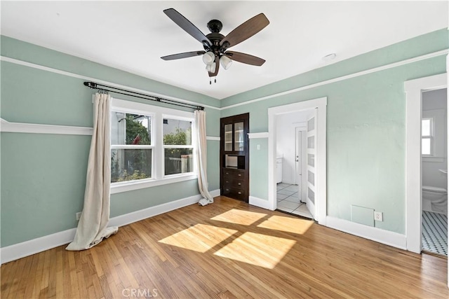 unfurnished bedroom featuring hardwood / wood-style flooring, ceiling fan, and ensuite bathroom