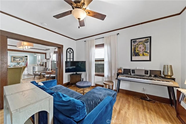 living room with ornamental molding, light hardwood / wood-style floors, and ceiling fan