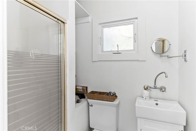 bathroom featuring a shower with door, sink, and toilet