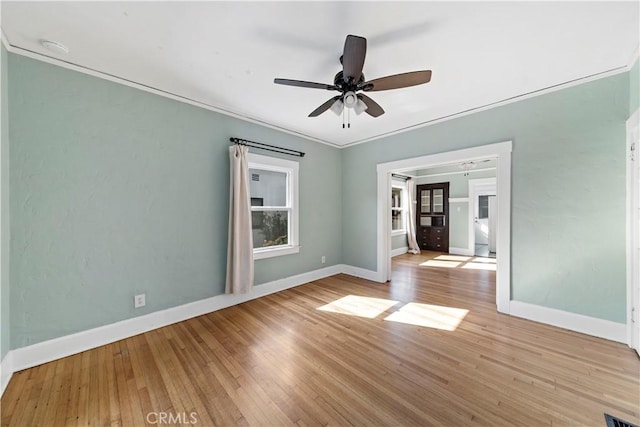 empty room with crown molding, ceiling fan, and light hardwood / wood-style floors