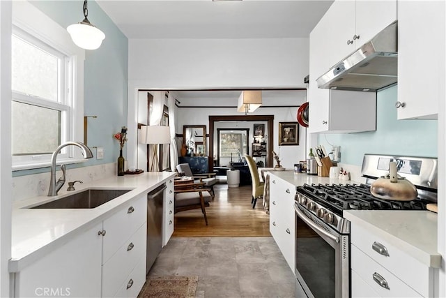 kitchen featuring white cabinetry, sink, decorative light fixtures, and appliances with stainless steel finishes