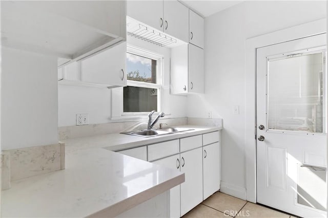 kitchen with sink, light tile patterned floors, and white cabinets