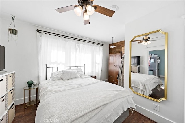 bedroom with dark hardwood / wood-style floors, stainless steel refrigerator, and ceiling fan