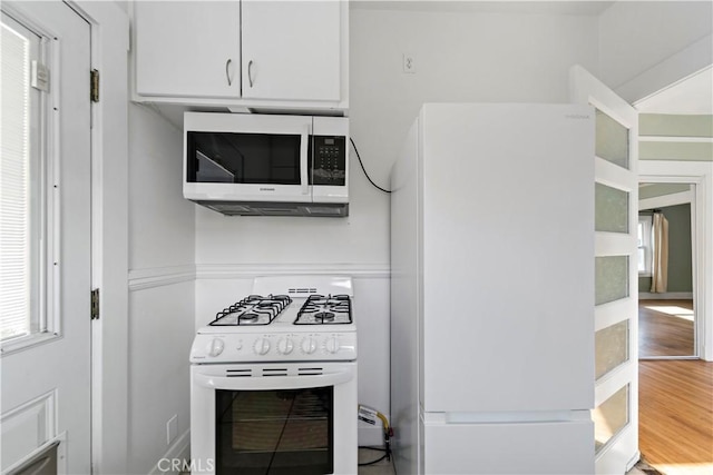 kitchen featuring white cabinetry, white appliances, and wood-type flooring