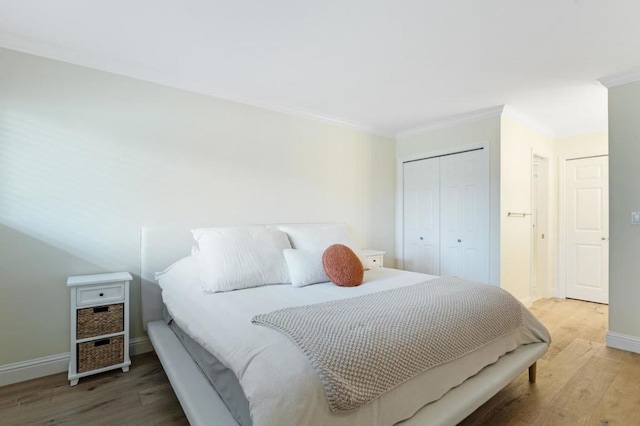 bedroom featuring ornamental molding, wood-type flooring, and a closet