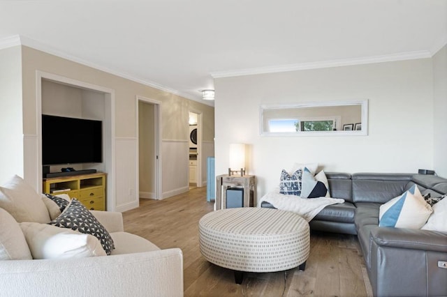 living room with crown molding, light hardwood / wood-style floors, and stacked washer and clothes dryer