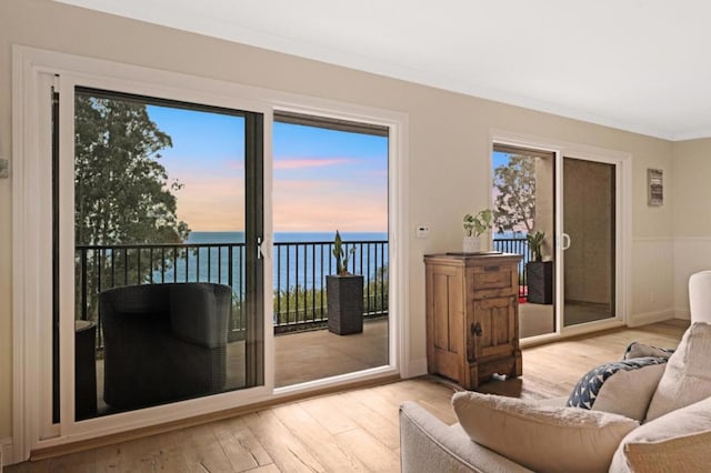 living room featuring a water view, crown molding, and light wood-type flooring