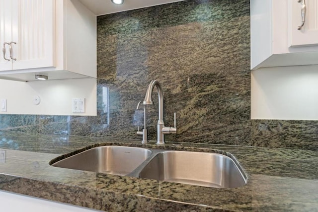 kitchen featuring backsplash, dark stone countertops, sink, and white cabinets