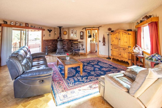 living room featuring light parquet flooring, a wealth of natural light, a textured ceiling, and a wood stove