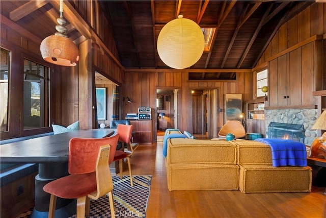 kitchen with wood ceiling, hardwood / wood-style flooring, vaulted ceiling with beams, wooden walls, and a high end fireplace