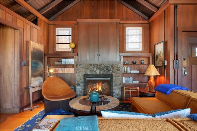 living area with lofted ceiling with beams, a healthy amount of sunlight, and wood walls