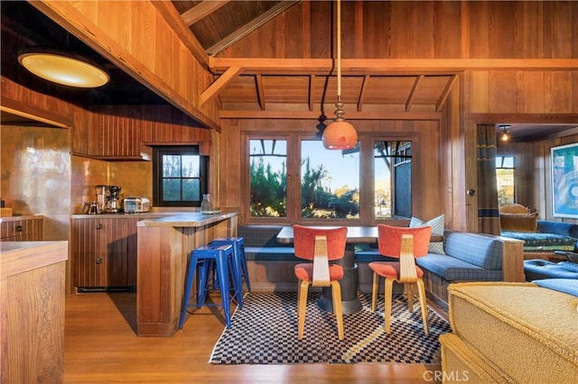 kitchen with wood ceiling, breakfast area, decorative light fixtures, beamed ceiling, and wood walls