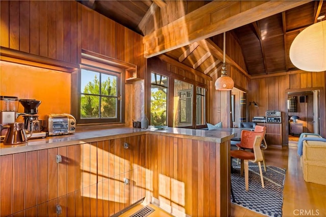 kitchen with wood ceiling, wooden walls, decorative light fixtures, and vaulted ceiling with beams