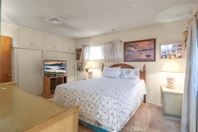 bedroom featuring light colored carpet and a textured ceiling