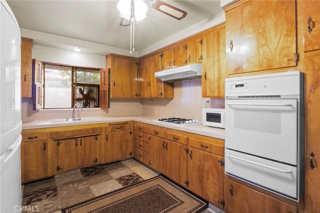 kitchen with tasteful backsplash, sink, white appliances, and ceiling fan