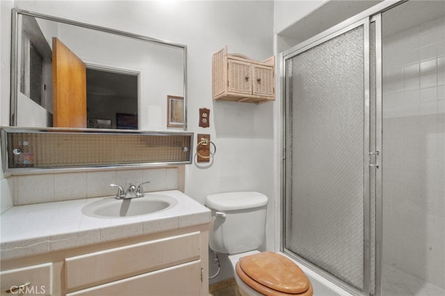 bathroom featuring tasteful backsplash, vanity, a shower with shower door, and toilet