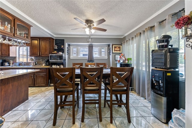 kitchen with crown molding, stainless steel microwave, dark brown cabinets, and backsplash