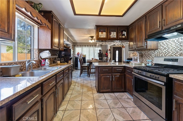 kitchen featuring sink, stainless steel gas stove, backsplash, dark brown cabinetry, and kitchen peninsula