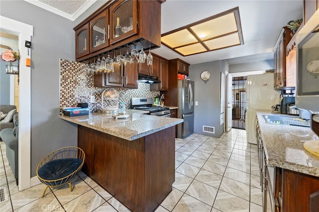 kitchen with light stone counters, appliances with stainless steel finishes, kitchen peninsula, and decorative backsplash