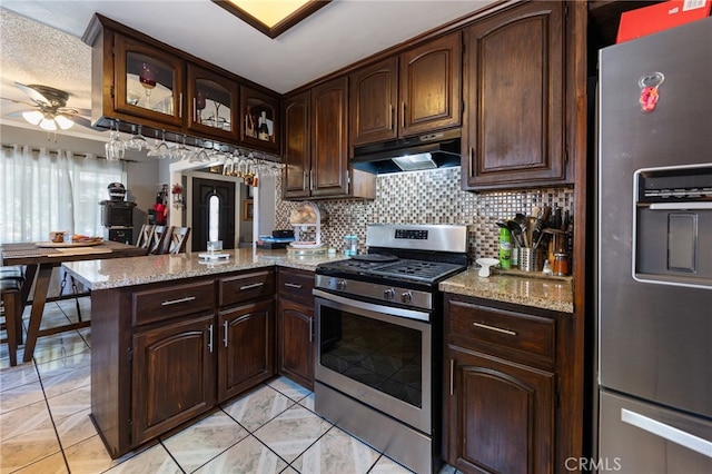 kitchen with appliances with stainless steel finishes, dark brown cabinetry, light stone counters, decorative backsplash, and kitchen peninsula