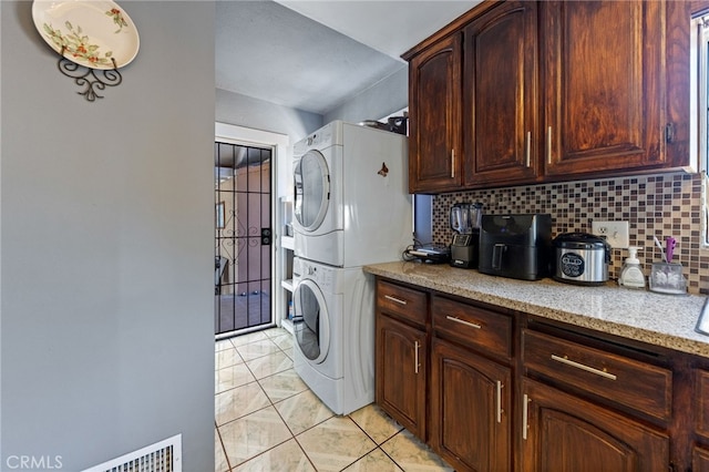 laundry room featuring light tile patterned flooring and stacked washer and clothes dryer