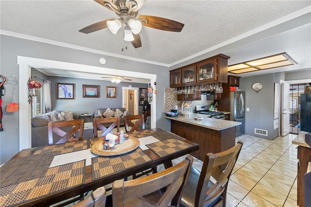 dining space with crown molding, ceiling fan, a textured ceiling, and light tile patterned floors