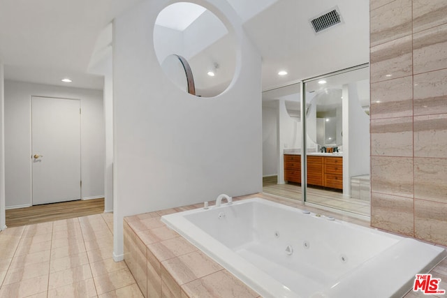 bathroom with vanity, tiled tub, and tile patterned flooring