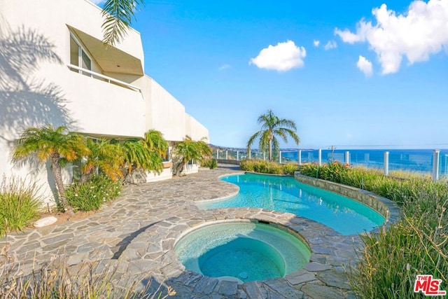 view of pool featuring a water view and an in ground hot tub