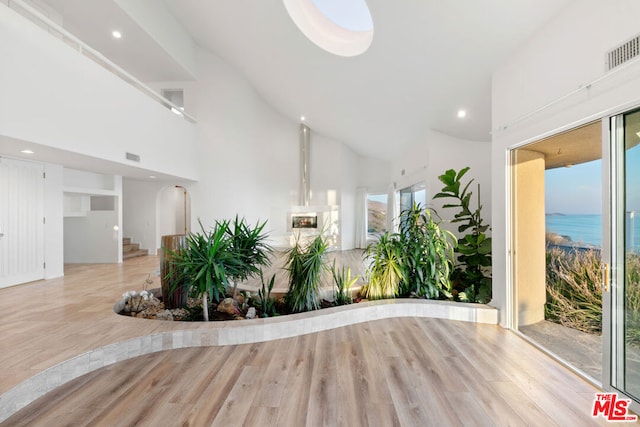 interior space featuring a water view, light hardwood / wood-style floors, and high vaulted ceiling